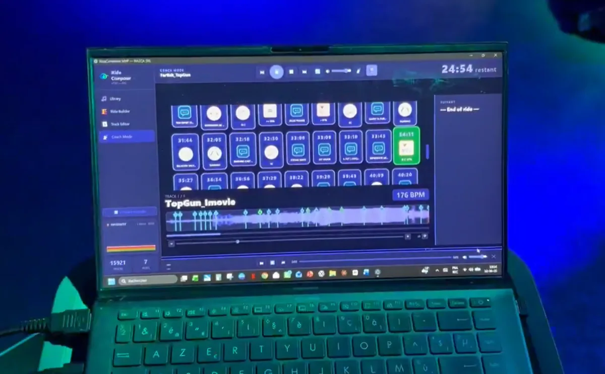 Un portable au pupitre d'une salle d'indoor cycling faisant tourner le Coach Mode de RideComposer, avec la grille des consignes, le morceau en cours et le temps restant
